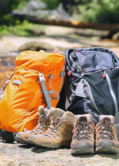 Hiking gear banner background in summer forest two backpacks and trek shoes boots for hikers couple camping travel outdoor adventure panoramic header.